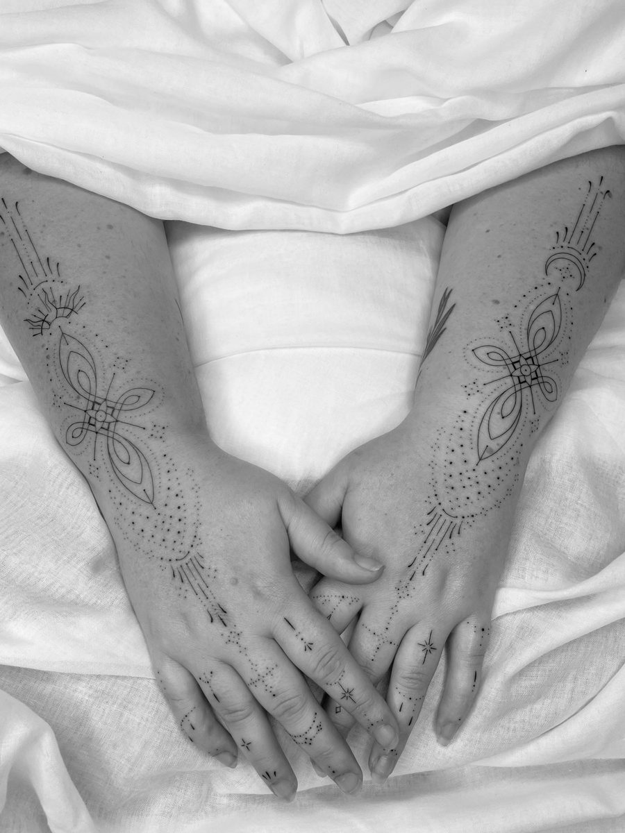 Symmetrical fine line tattoos across both hands and forearms by Caroline Lindskov