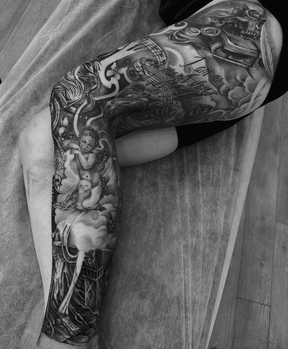 Cherub and gothic skull leg sleeve tattoo in black and grey by Charlie Lund