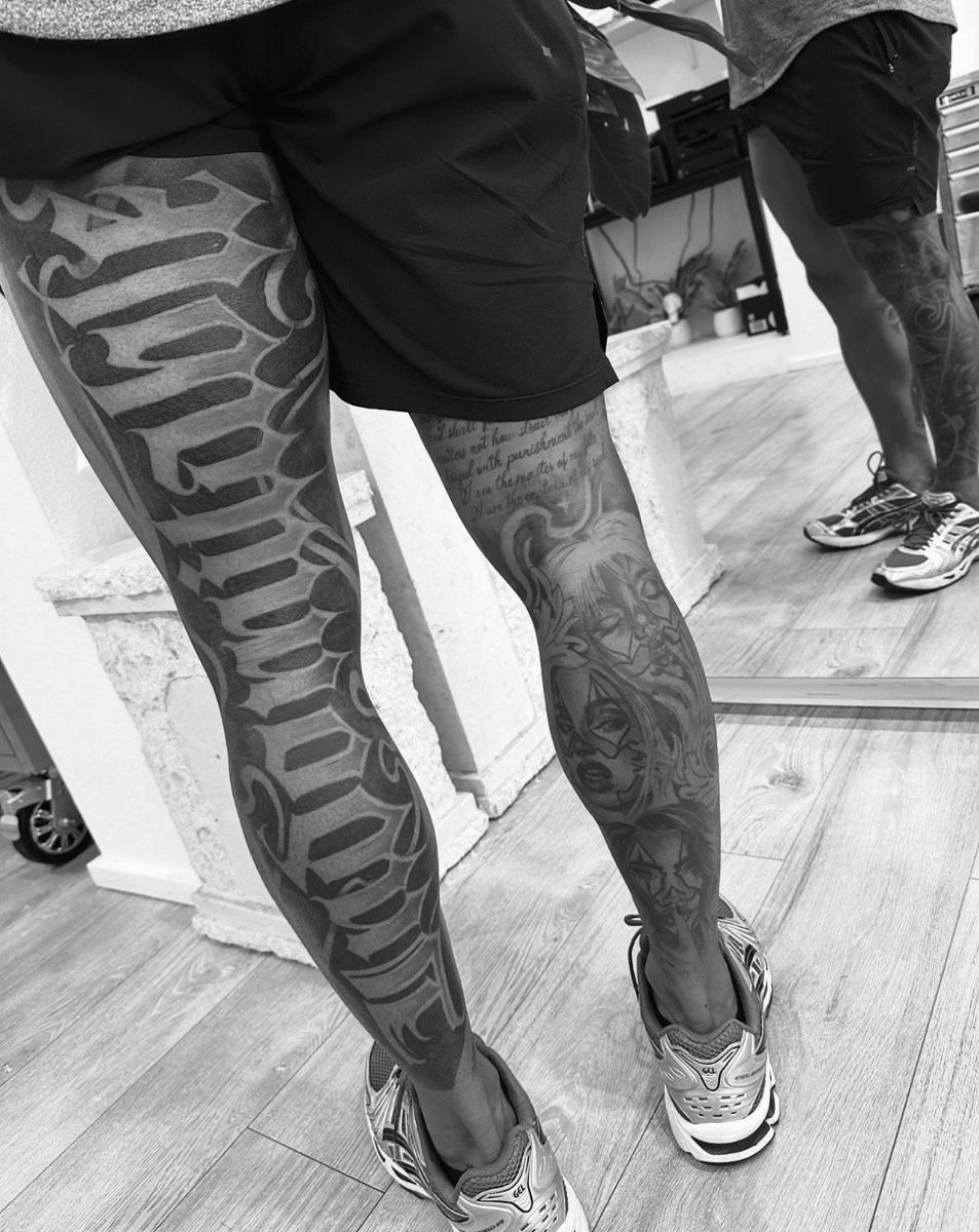 Calligraphic lettering and joker portrait leg tattoos by Charlie Lund