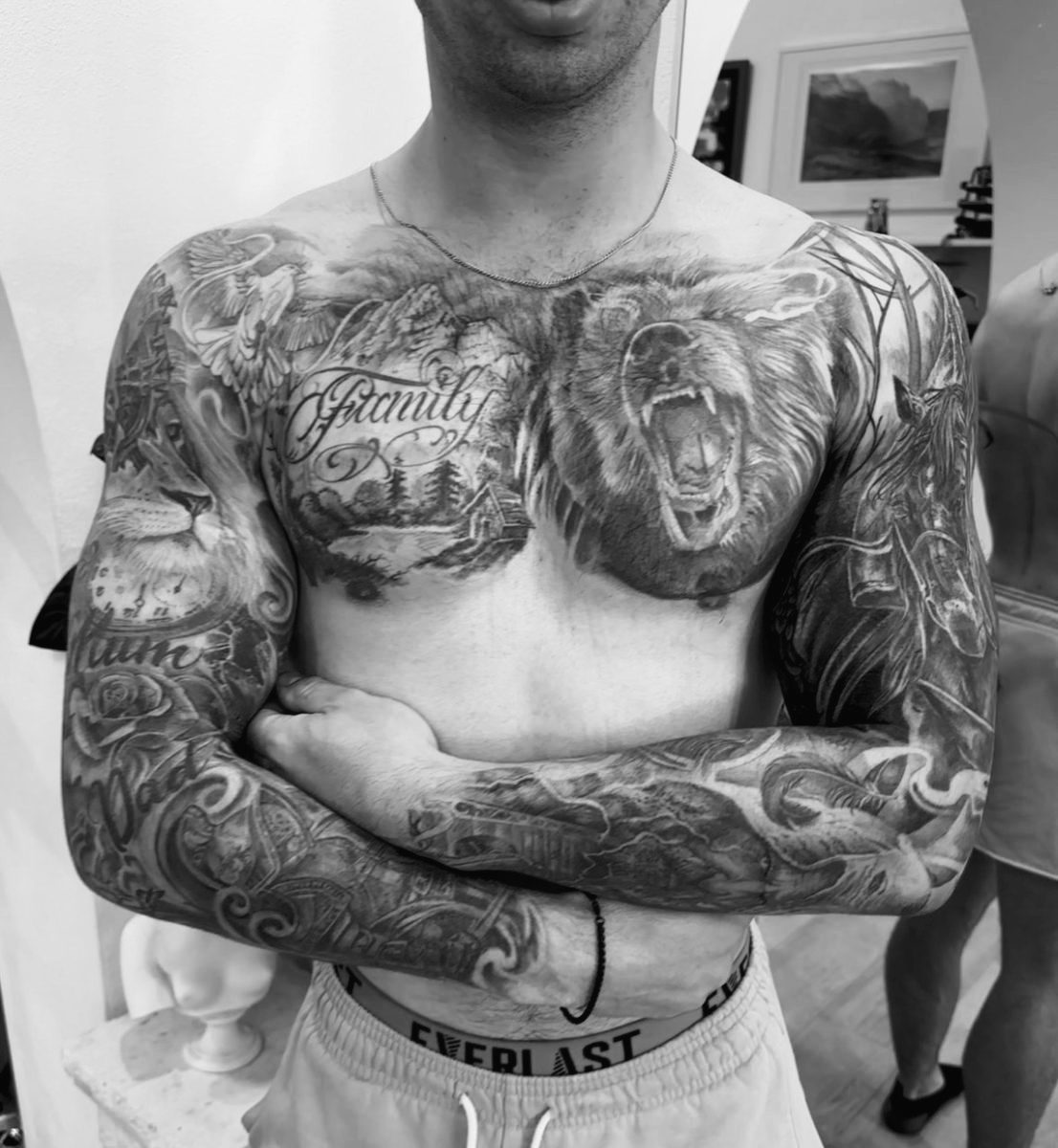 Full chest and sleeve tattoo featuring bear, lion and family lettering by Charlie Lund